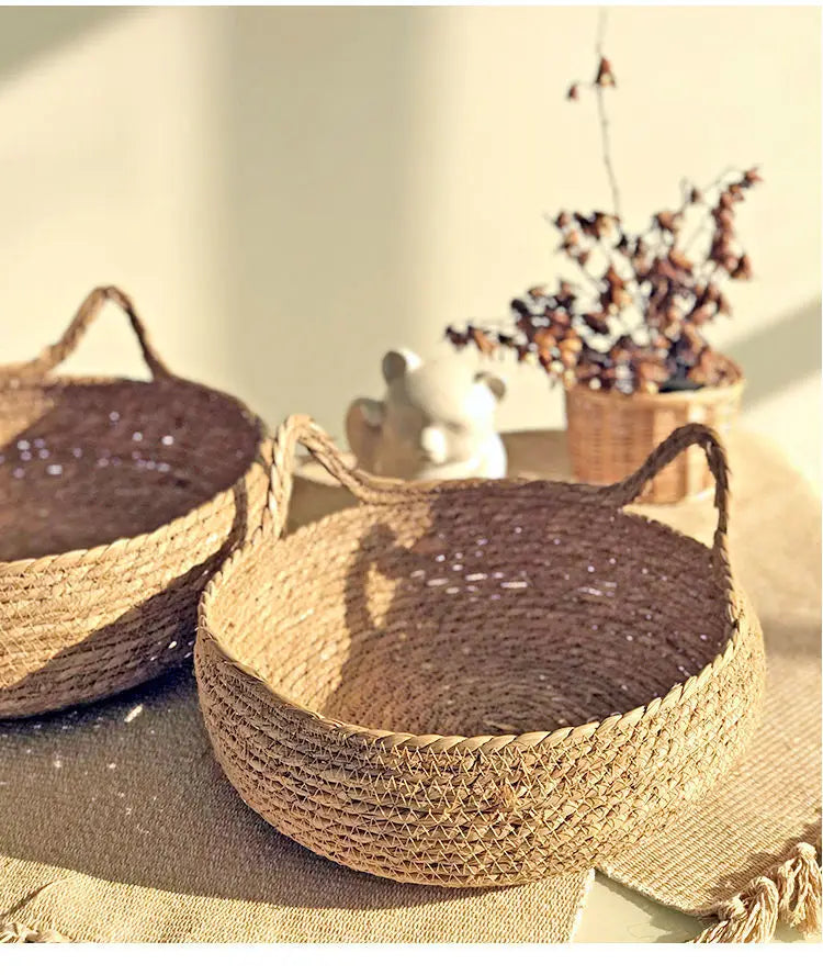 Panier pour chat en rotin rond avec coussin rond foncé, poignées en corde.
