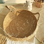 Panier pour chat en rotin rond, intérieur tressé, poignées en corde, coussin absent.