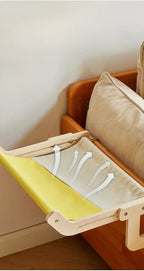 Nid suspendu en bois avec coussin jaune et blanc sur un accoudoir de canapé